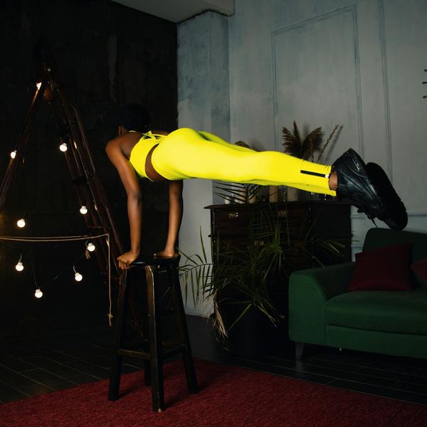 Woman in a fluid yoga pose in a dark room with blue light.